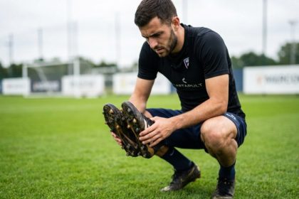 joueur inspectant des crampons adidas sur le terrain de foot